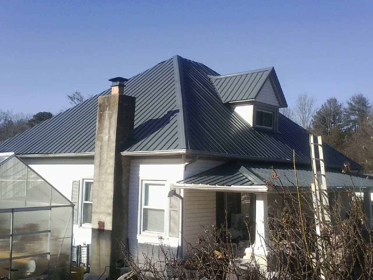 Dark blue standing seam metal roof on a white farmhouse with dormer — Slate & Tile Roof Repair by Roofing Brothers in Trafalgar