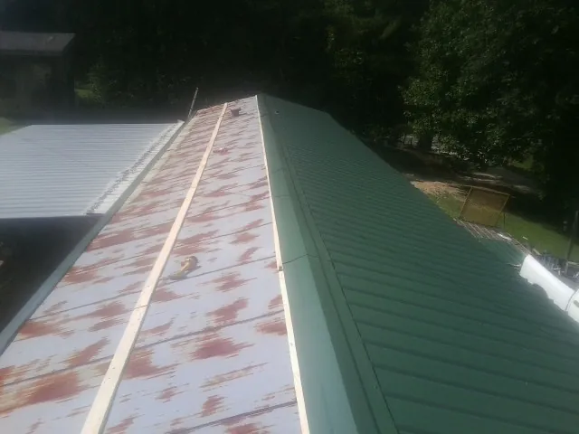 Old rusted panels beside newly installed green metal roofing — Wind Damage Roof Repair by Roofing Brothers in Trafalgar