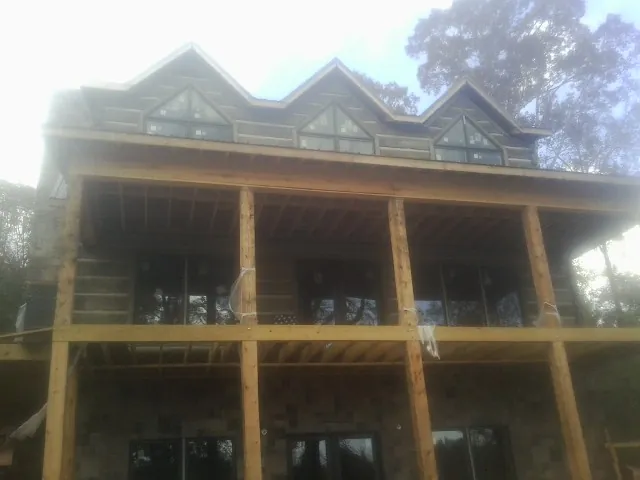 Dormers and porch framing on a large log home under construction — Roof Coating work by our crew in Trafalgar