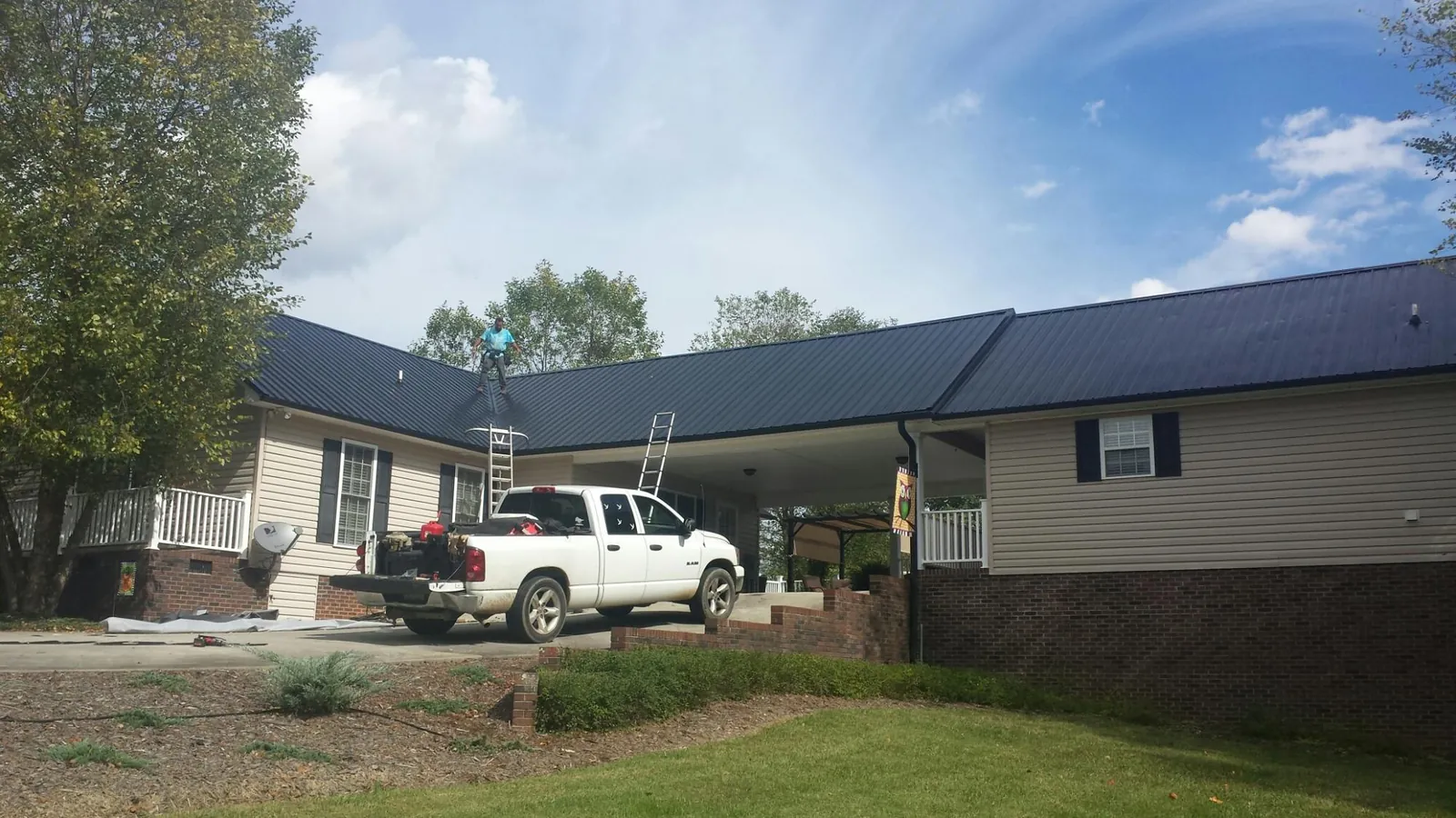 Black metal roof over a home and attached breezeway with ladders set in Trafalgar