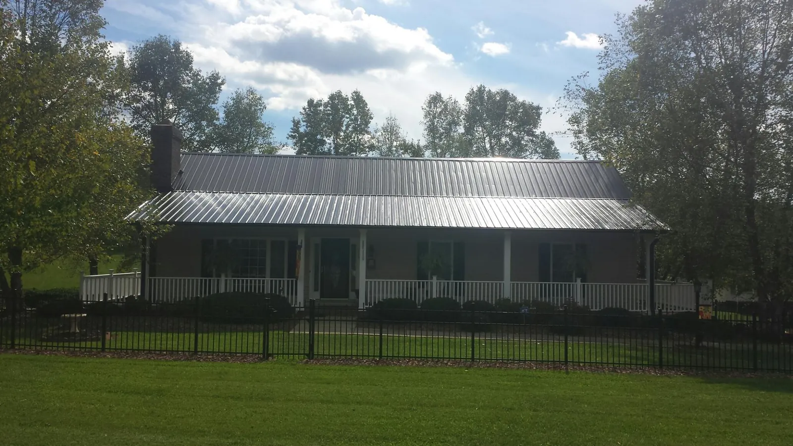 Gray metal roof on a brick ranch with a full width front porch — Gutter Guard Installation work by our crew in Trafalgar