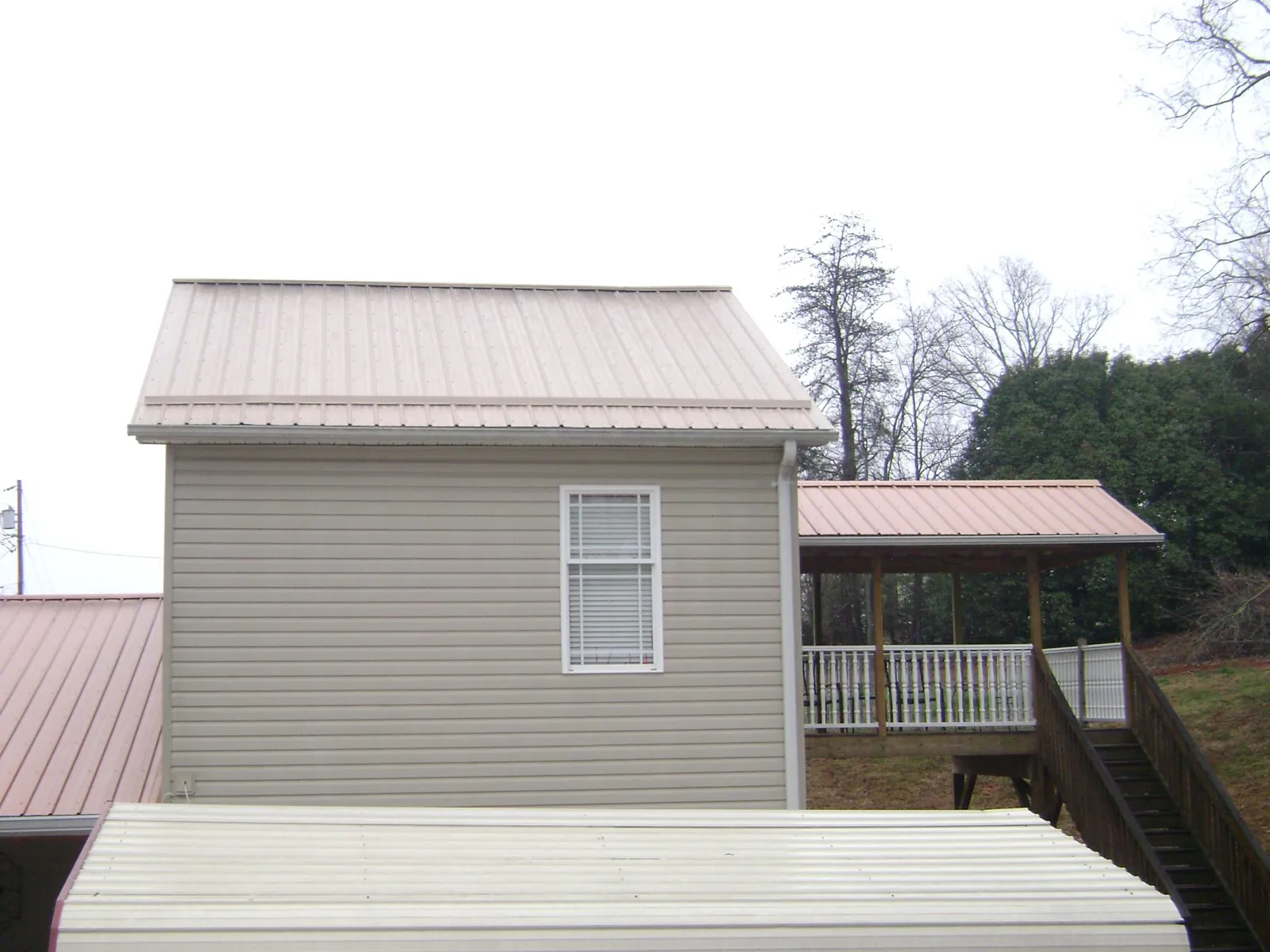 Tan metal roofs on a two story addition and attached porch, from a Roof Replacement job in Trafalgar