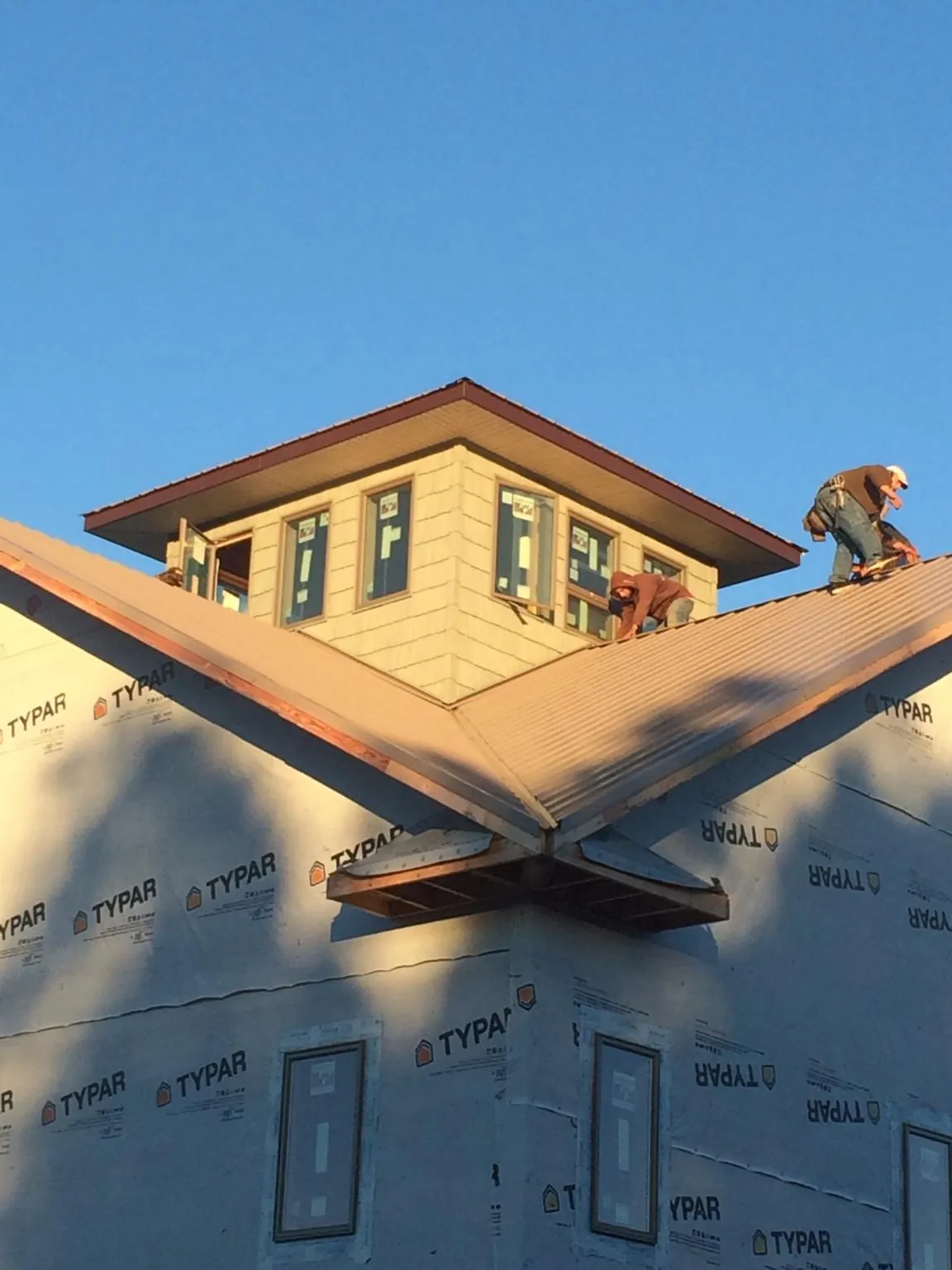 Roofers working around a rooftop cupola on a new metal roof at sunset — Roof Waterproofing in Trafalgar by Roofing Brothers